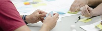 As mans dunha persoa sosteñen un papel mentres as doutras están apoiadas sobre unha mesa
